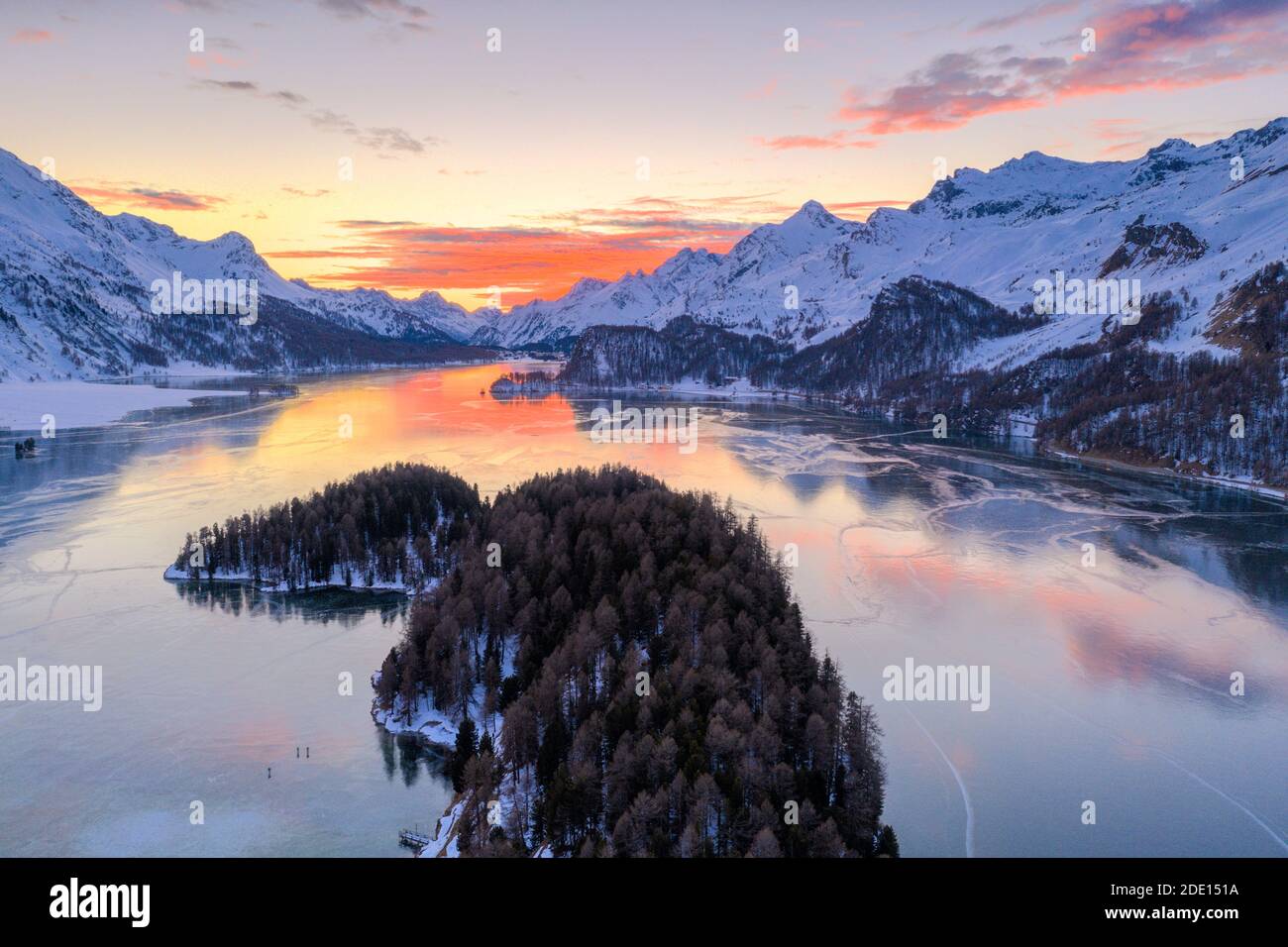 Vue aérienne du ciel brûlant au coucher du soleil sur le lac gelé Sils et les montagnes enneigées, col de Maloja, canton de Graubunden, Alpes suisses, Suisse, Europe Banque D'Images