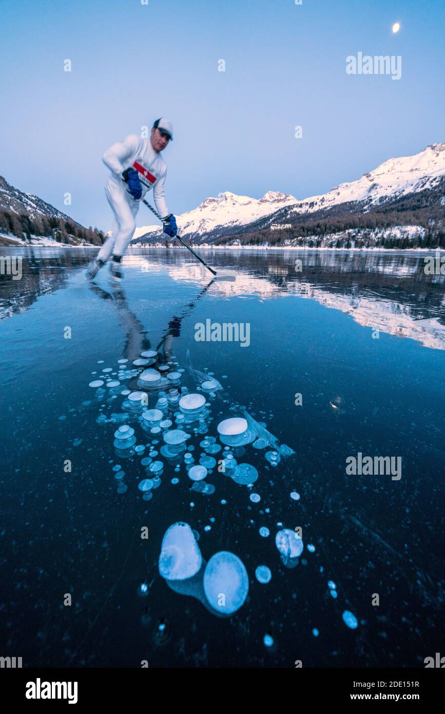 Joueur de hockey sur glace homme patinant sur le lac Sils couvert de bulles de glace au crépuscule, Engadine, canton de Graubunden, Suisse, Europe Banque D'Images