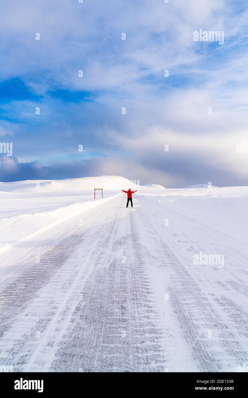 Homme heureux avec des bras levés debout sur la route enneigée glacée vers Nordkapp (Cap Nord), Troms og Finnmark, Norvège du Nord, Scandinavie, Europe Banque D'Images