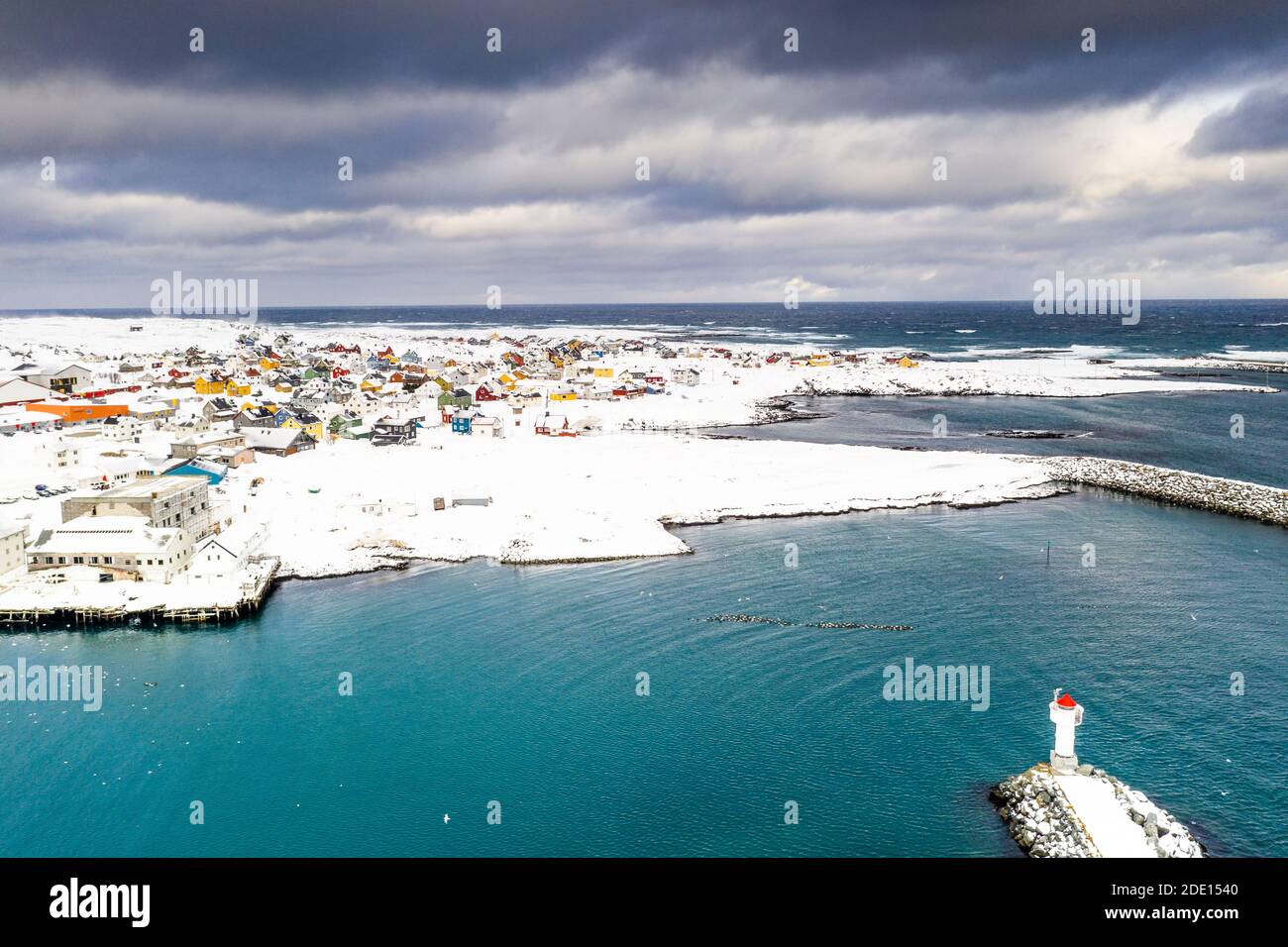 Nuages orageux au-dessus du phare et village de Berlevag recouvert de neige, mer de Barents, péninsule de Varanger, Troms og Finnmark, Norvège, Scandinavie, Europe Banque D'Images