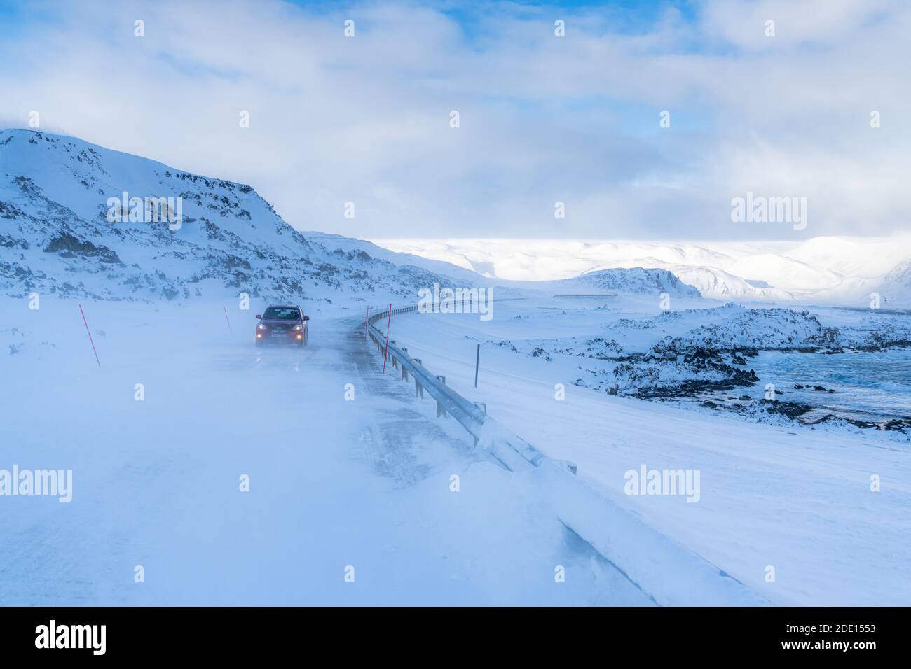 Voiture voyageant sur une route glacée vide le long de la côte enneigée de la mer froide de Barents, l'océan Arctique, la péninsule de Varanger, Finnmark, la Norvège, la Scandinavie, l'Europe Banque D'Images