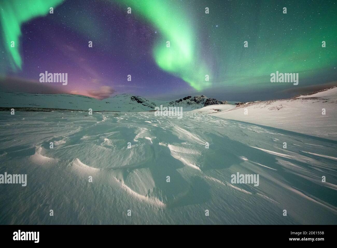 Neige gelée éclairée par les lumières vertes des aurores boréales (Aurora Borealis) dans la nuit froide de l'Arctique, île de Mageroya, Nordkapp, Norvège Banque D'Images