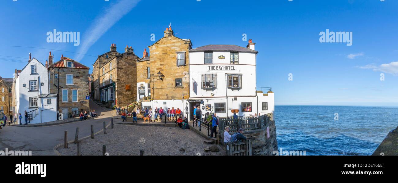 Vue sur le White Washed Bay Hotel et les visiteurs au port de Robin Hood Bay, North Yorkshire, Angleterre, Royaume-Uni, Europe Banque D'Images