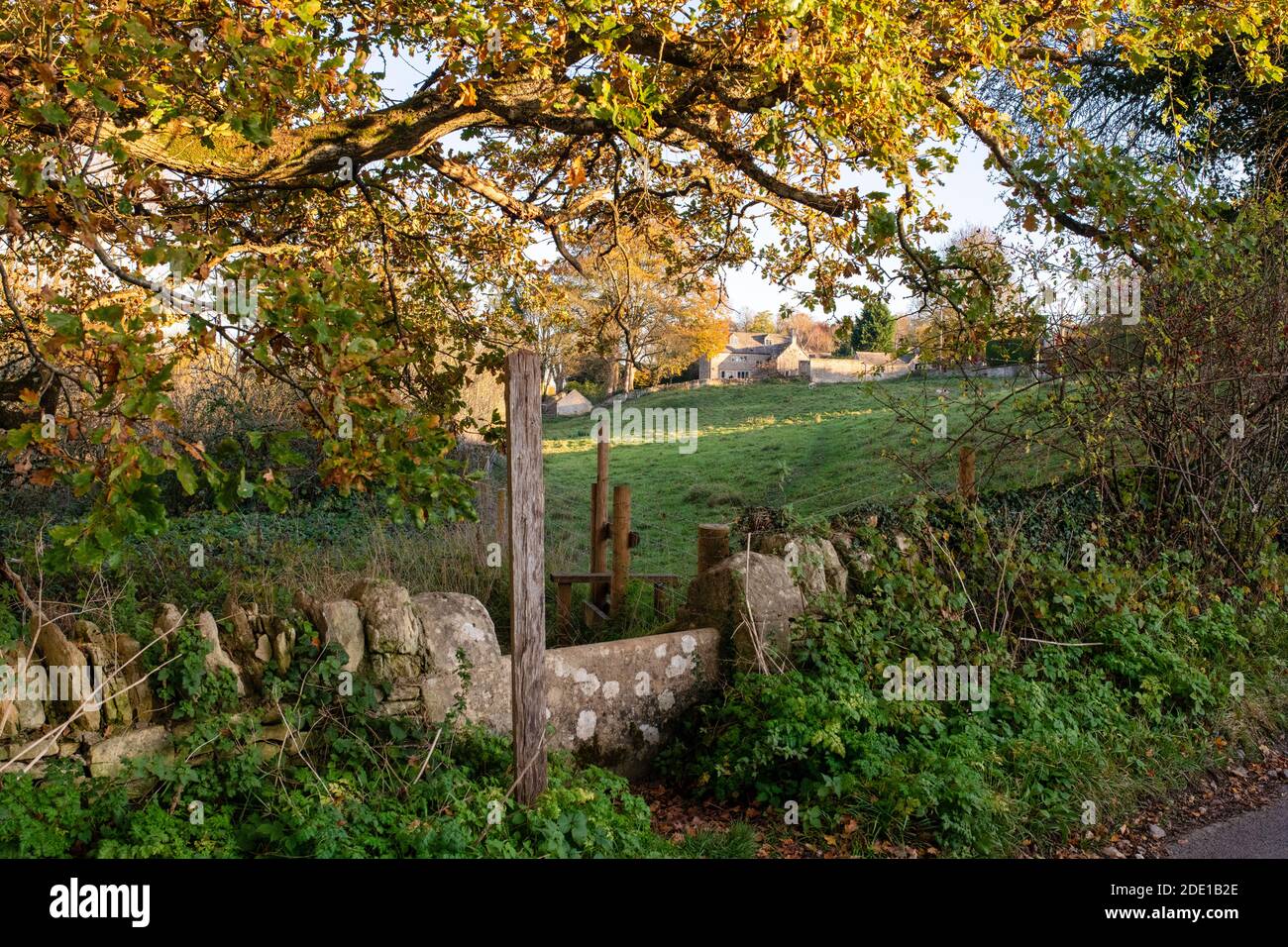 Sentier public à travers un mur de pierre dans le village de Sherborne dans l'automne après-midi lumière du soleil. Sherborne, Cotswolds, Gloucestershire, Angleterre Banque D'Images