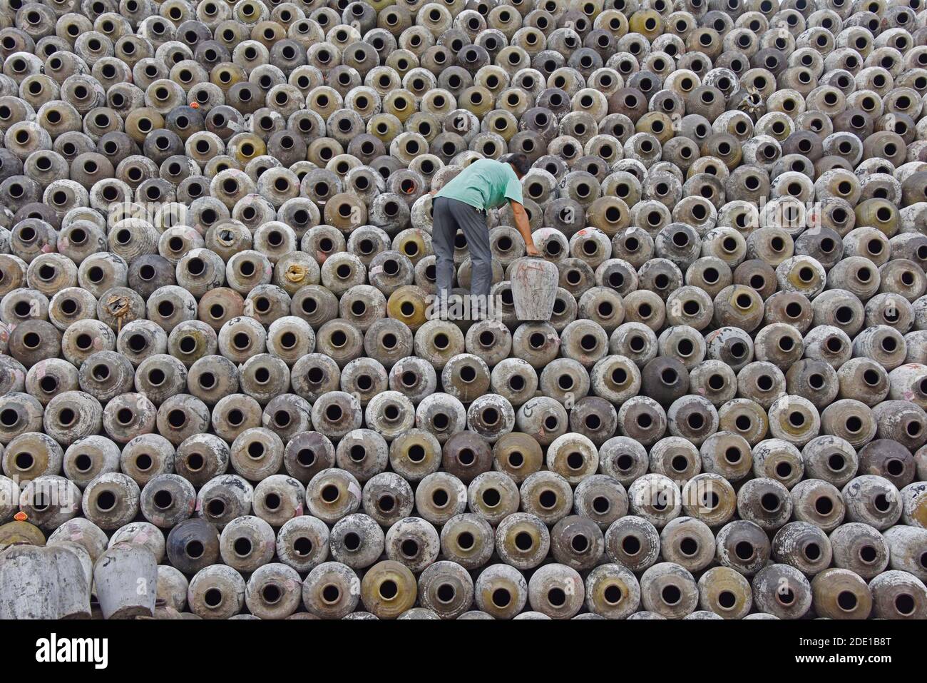 Homme empilant des pots de vin sur la grande pile dans un domaine viticole, Linhai, province de Zhejiang, Chine Banque D'Images