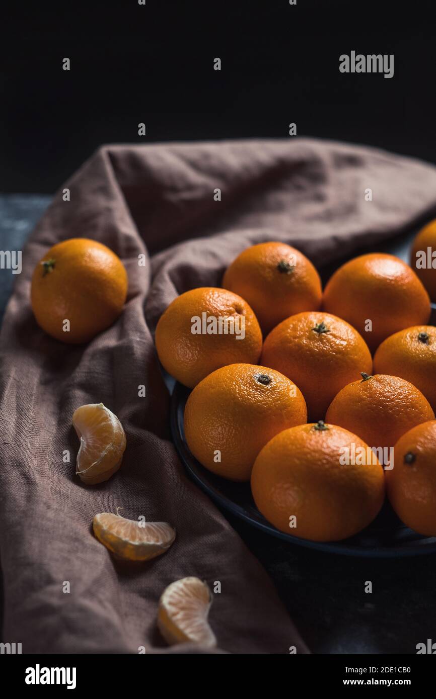 Pile de mandarine orange mûre ronde non pelée dans une assiette. Banque D'Images