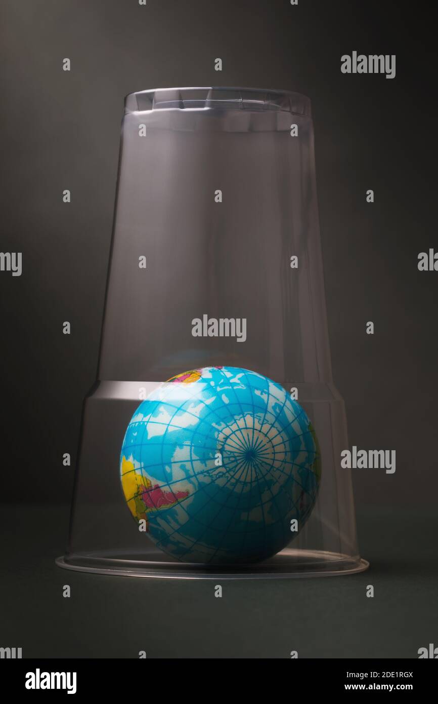 Un jouet en forme de globe est recouvert d'un verre en plastique. Concept sur le thème de l'obstruction de la planète avec du plastique. Banque D'Images