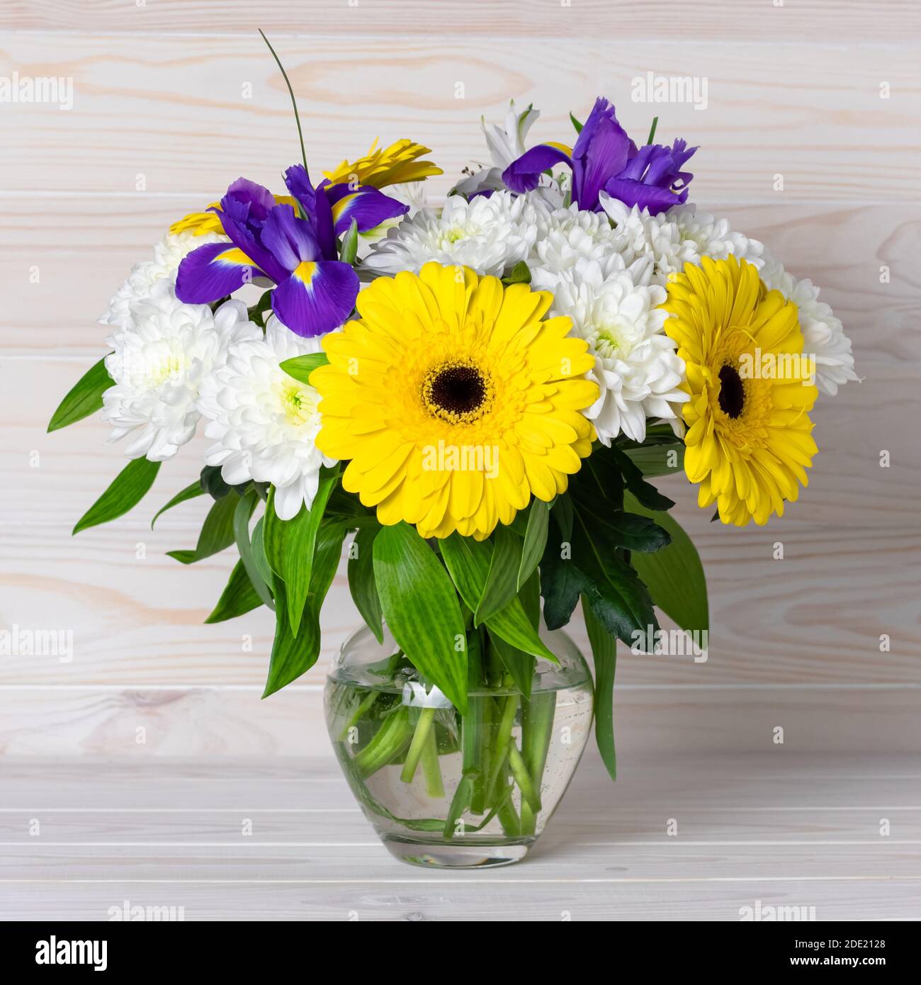 Un bouquet de fleurs d'automne dans un vase en verre sur une table en bois clair. Motif fleuri, décoration par éléments dans un style rustique. Encore vie, carte postale carrée. Banque D'Images