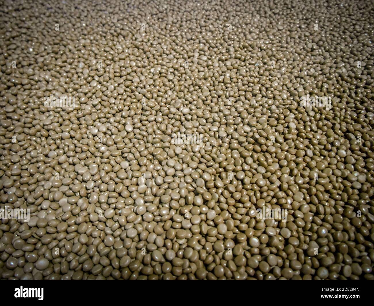 Résine plastique en polyéthylène recyclé post-consommation brun et gris en vrac granulés dans un récipient de stockage Banque D'Images