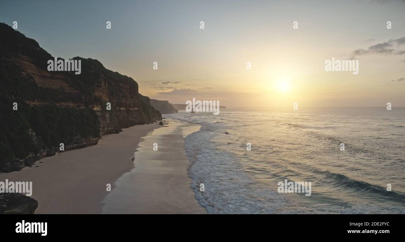 Lever du soleil sur les vagues de l'océan avec un paysage tropical paradisiaque. Scène tropicale sans nature avec la côte rocheuse. Magnifique paysage ensoleillé de falaise de sable de la plage de Bawana, l'île de Sumba, Indonésie vue aérienne Banque D'Images