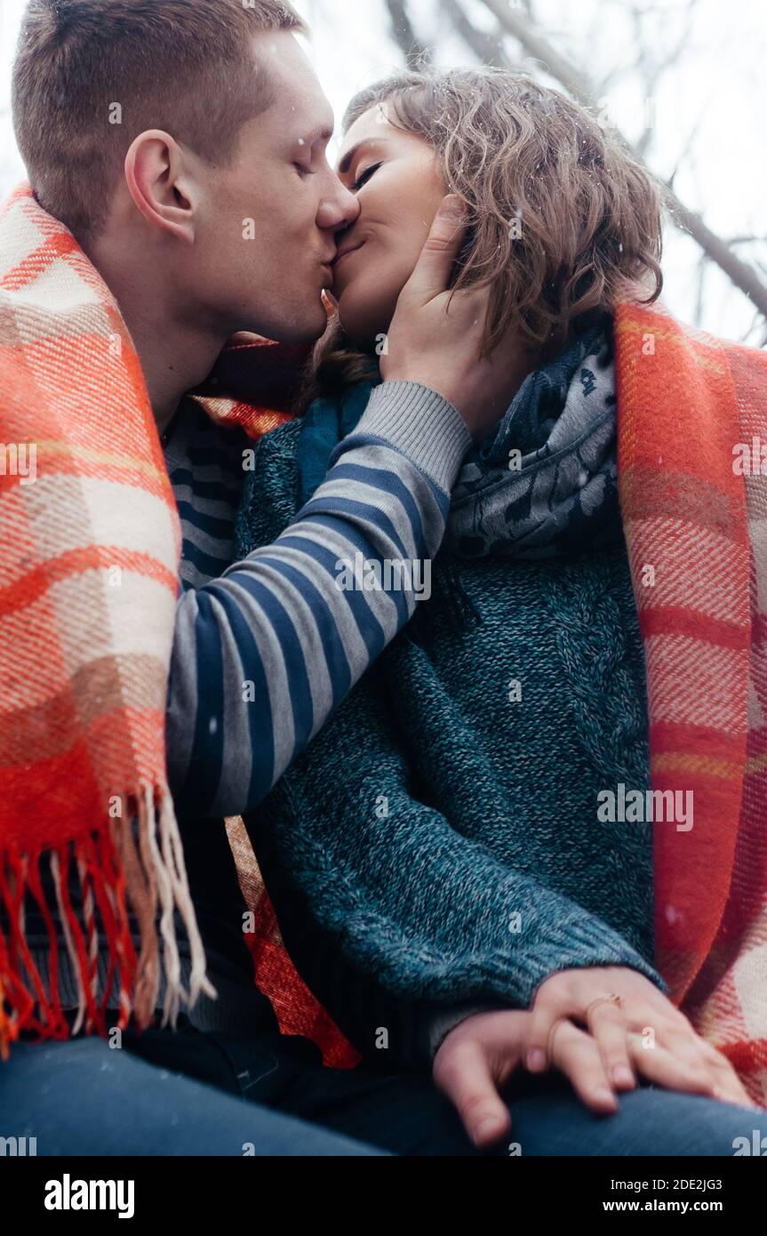 Noël, saison et concept de personnes - couple heureux assis couvert d'une  couverture et de baisers tenant la main de l'autre dehors dans le parc  d'hiver Photo Stock - Alamy