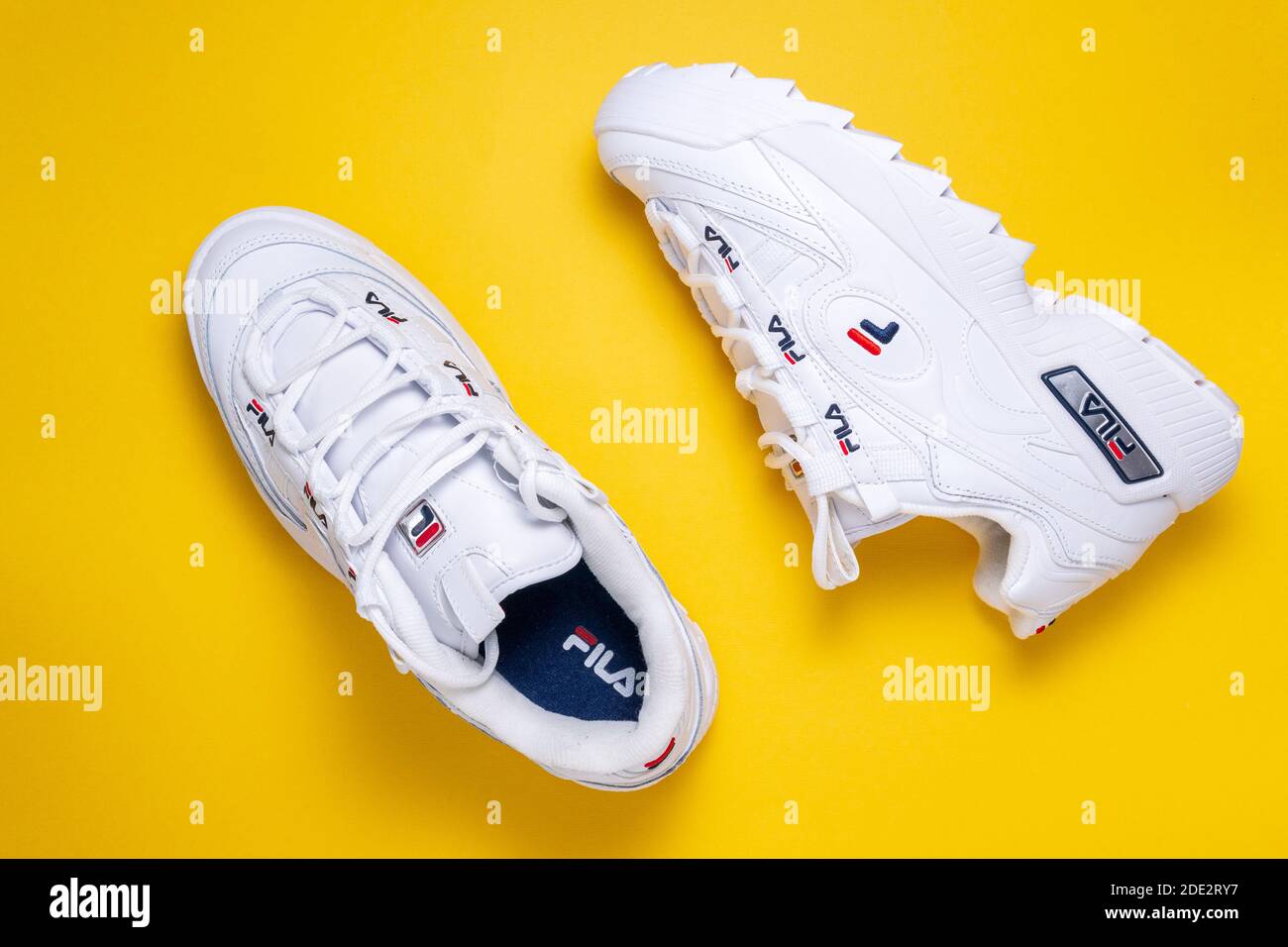 Tyumen, Russie-27 novembre 2020 : SNEAKERS blanches FILA pour femmes sur fond jaune coloré, Fila est l'une des plus grandes sociétés de vêtements de sport au monde. Banque D'Images