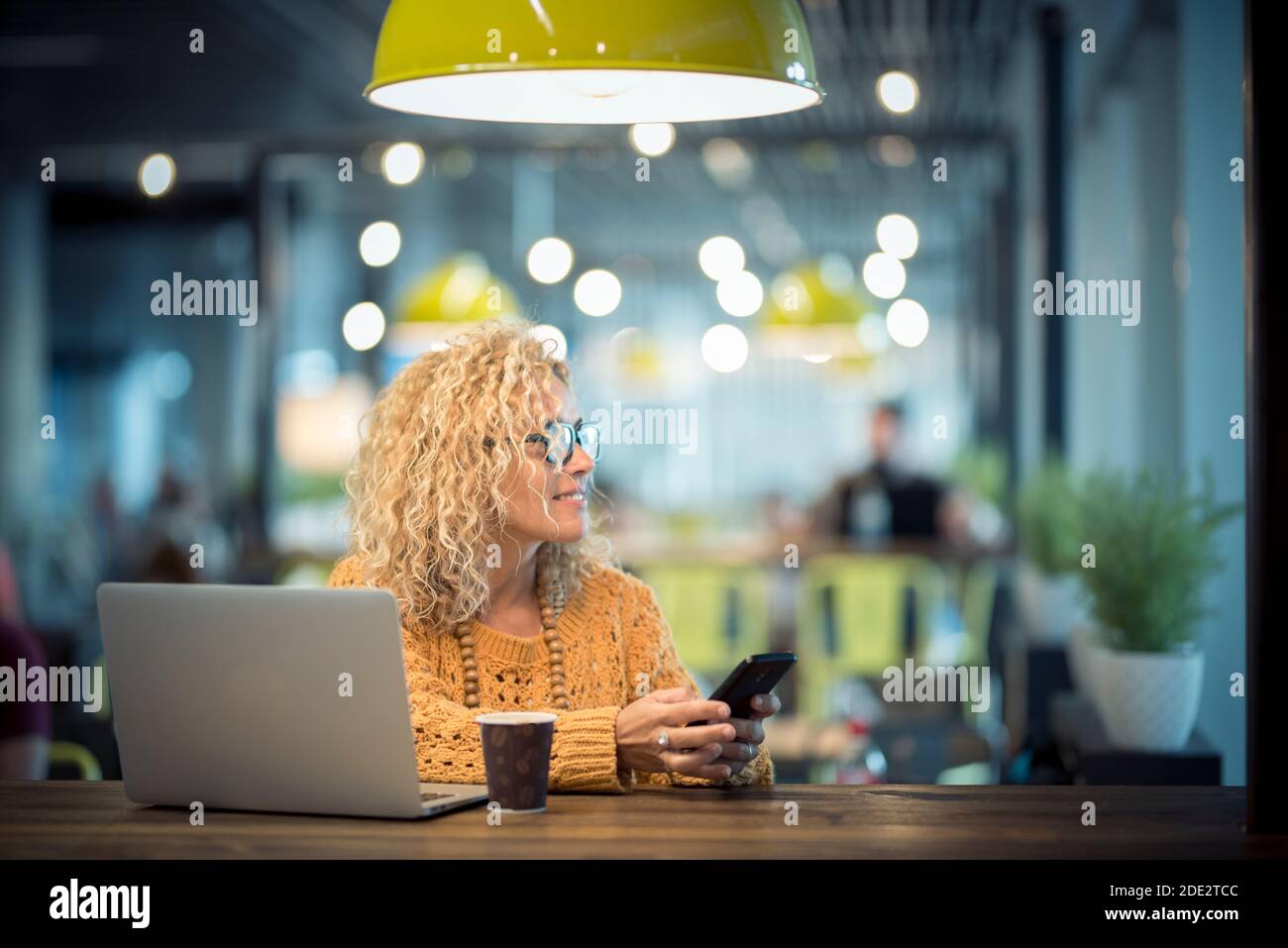 Une jeune femme adulte moderne voyage et travaille avec la technologie de roaming téléphone en ligne et ordinateur portable dans le café de bureau gratuit de l'aéroport porte - personnes et sma Banque D'Images