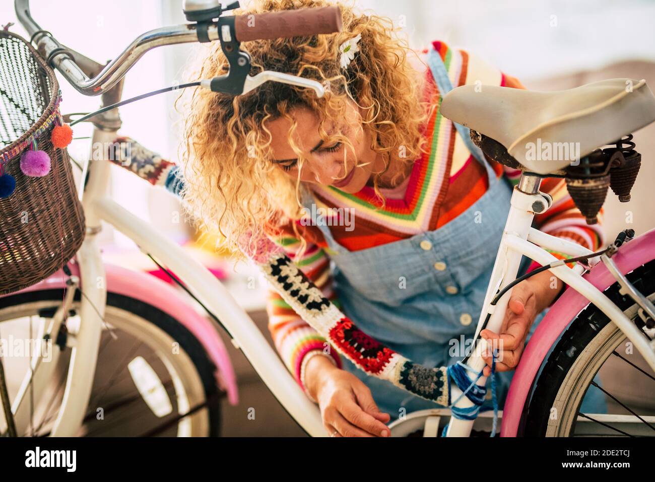 Belle femme adulte faire bricolage réparation et restauration à la maison d'un vélo utilisant de la laine de couleur - concep tof personnes en intérieur, activités de loisirs en verrouillage Banque D'Images