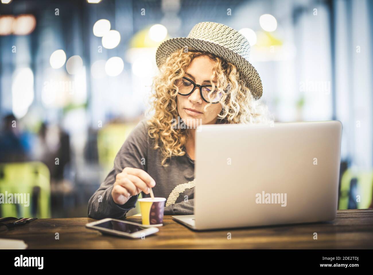 Belle jeune femme adulte au travail avec ordinateur portable coimputer dedans un café restaurant à l'aéroport en attente de son vol pour voyager - numérique nomade et mod Banque D'Images