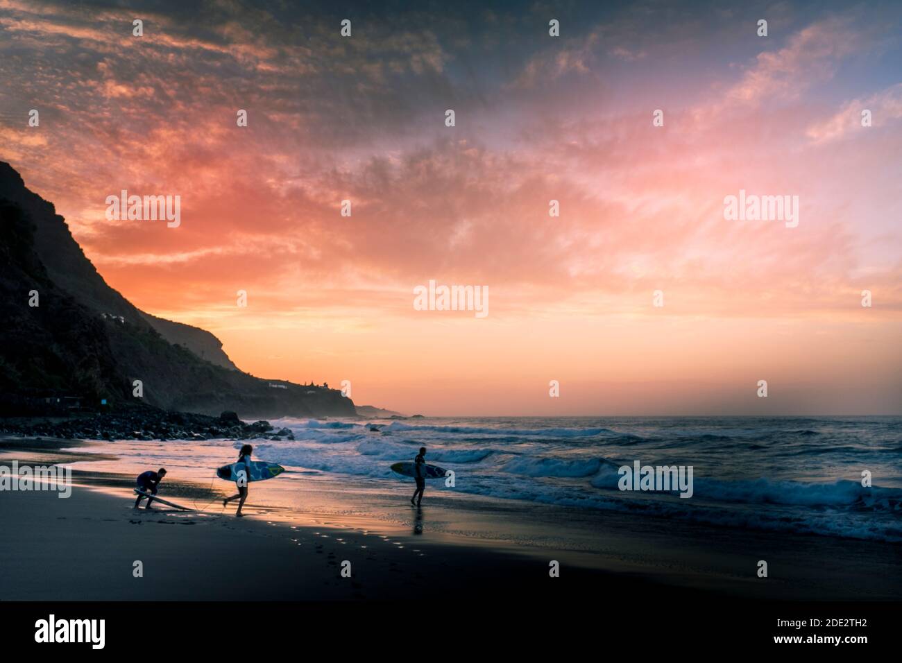 Un coucher de soleil aux couleurs incroyables sur la plage avec groupe de surfeurs aller à l'eau - sport de l'océan en été vacances pour les personnes actives Banque D'Images