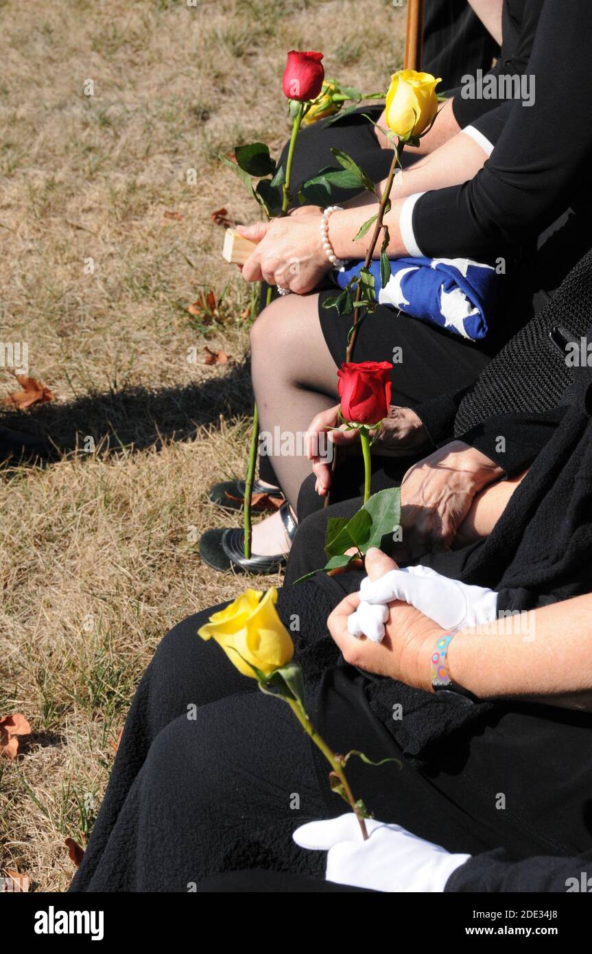 Famille tenant la main avec un drapeau américain plié à a funérailles militaires Banque D'Images