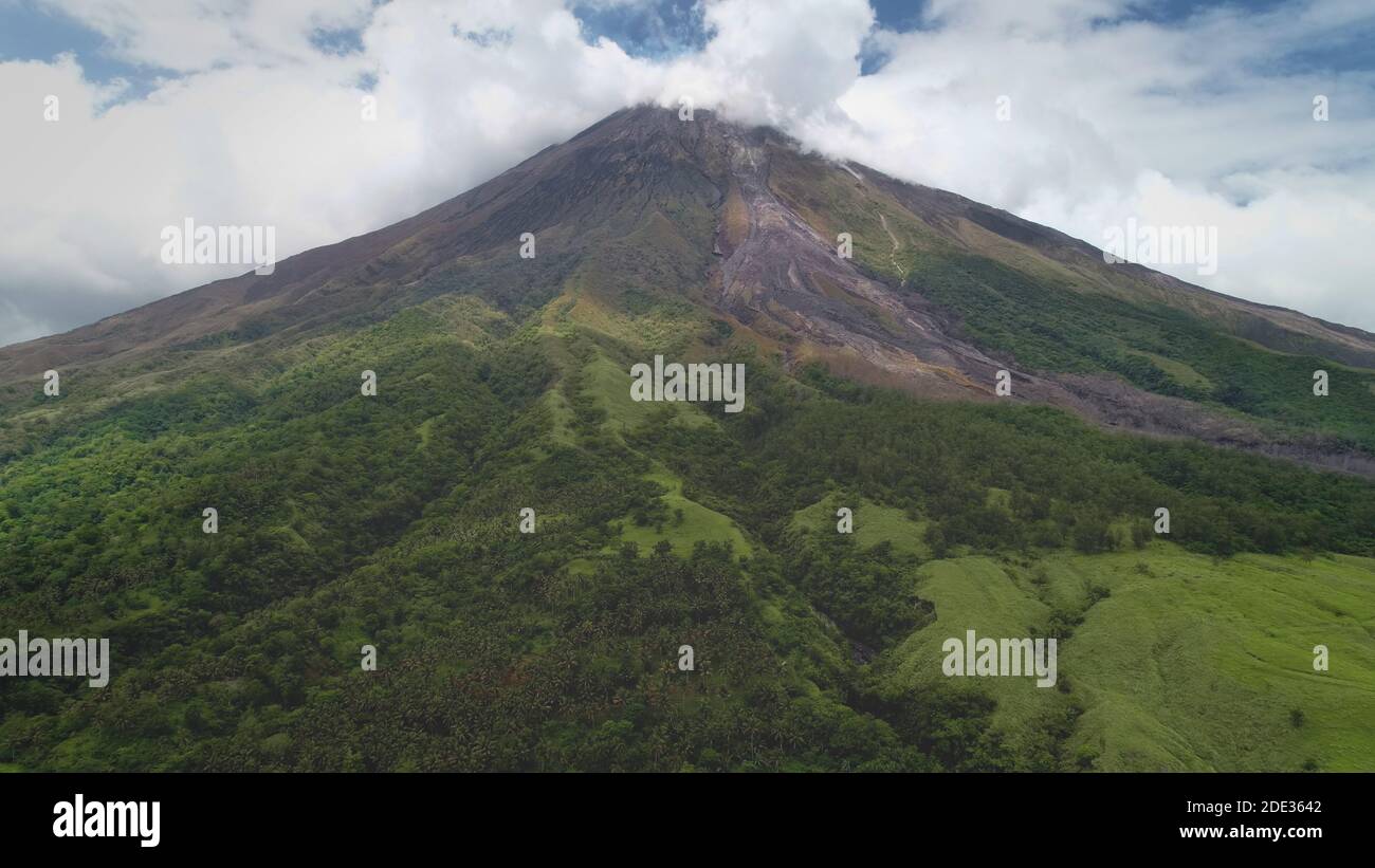 Gros plan volcan éruption nuages de brume aérienne. Montagne d'herbe verte avec sentier de randonnée. Philippines point de repère du mont Mayon, campagne de Legazpi. Personne paysage de la nature au brouillard. Tir de drone cinématographique Banque D'Images