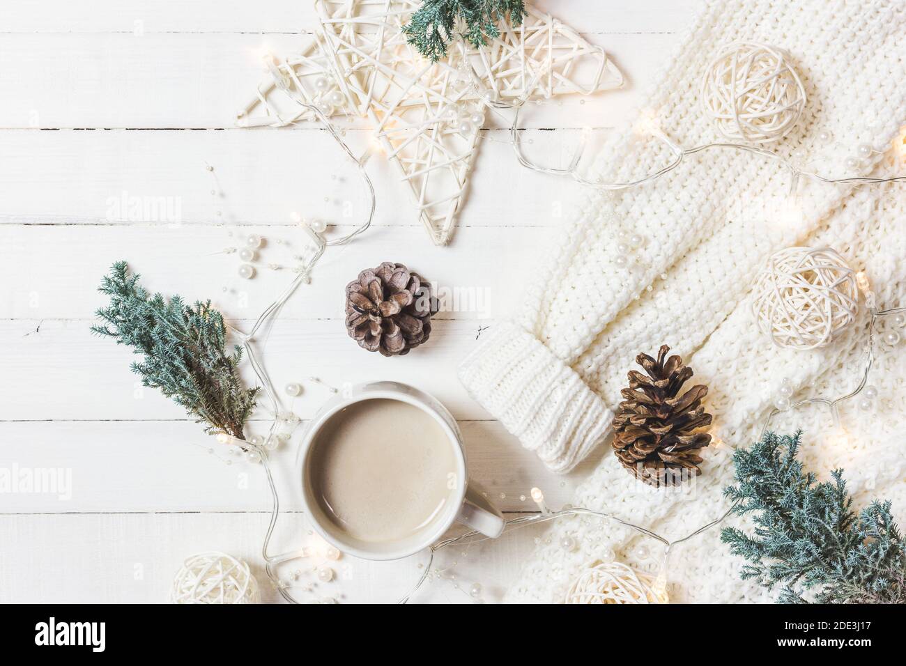 Composition de Noël. Tasse de café, chandail de mode pour femmes, branches de sapin et ornements sur fond blanc en bois. Hiver, concept de vacances. Pose à plat Banque D'Images