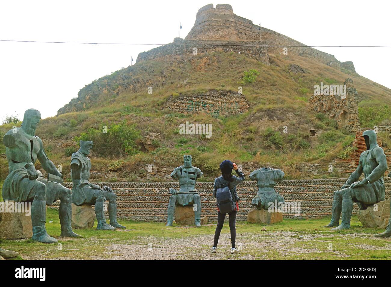 Femme voyageur regardant la forteresse de Gori depuis le Foothill entouré par le Mémorial des sculptures des héros guerriers géorgiens, ville de Gori, Geor Banque D'Images