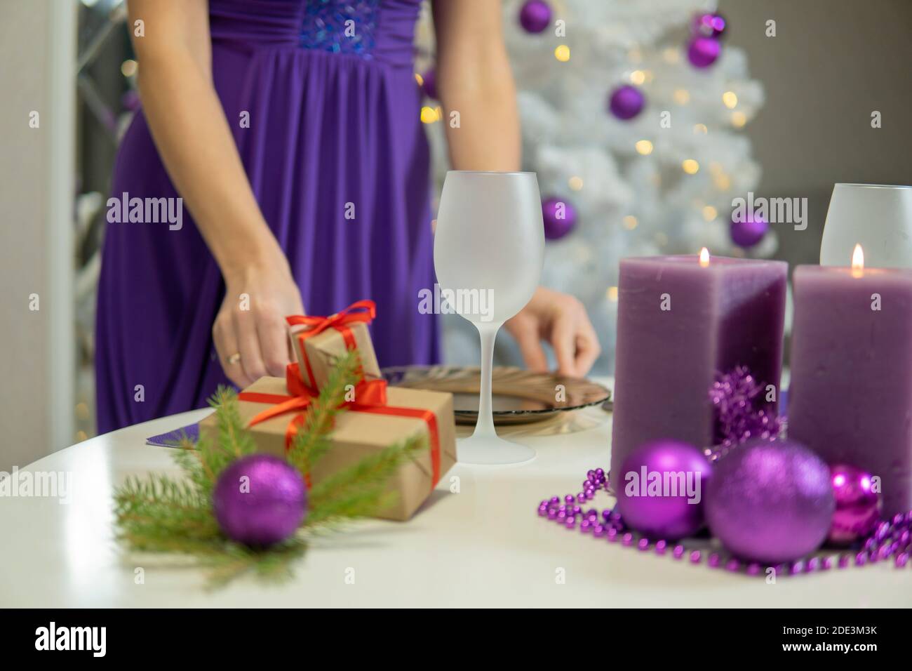 Fille fait la décoration de table de Noël avec des cadeaux et des bougies pourpres.. De haute qualité Banque D'Images