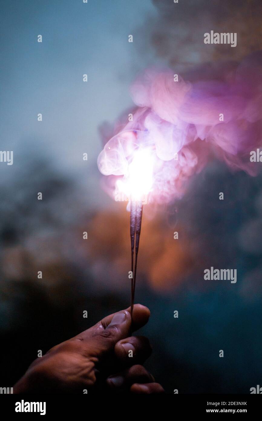 Personne tenant un Sparkler illuminé coloré pendant la nuit Banque D'Images