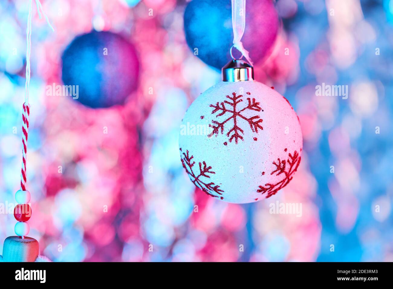 Boule de Noël ornée de flocons de neige rouges et de décorations sphériques  scintillantes bleues pour un sapin suspendu devant l'appareil photo sur  fond coloré Photo Stock - Alamy