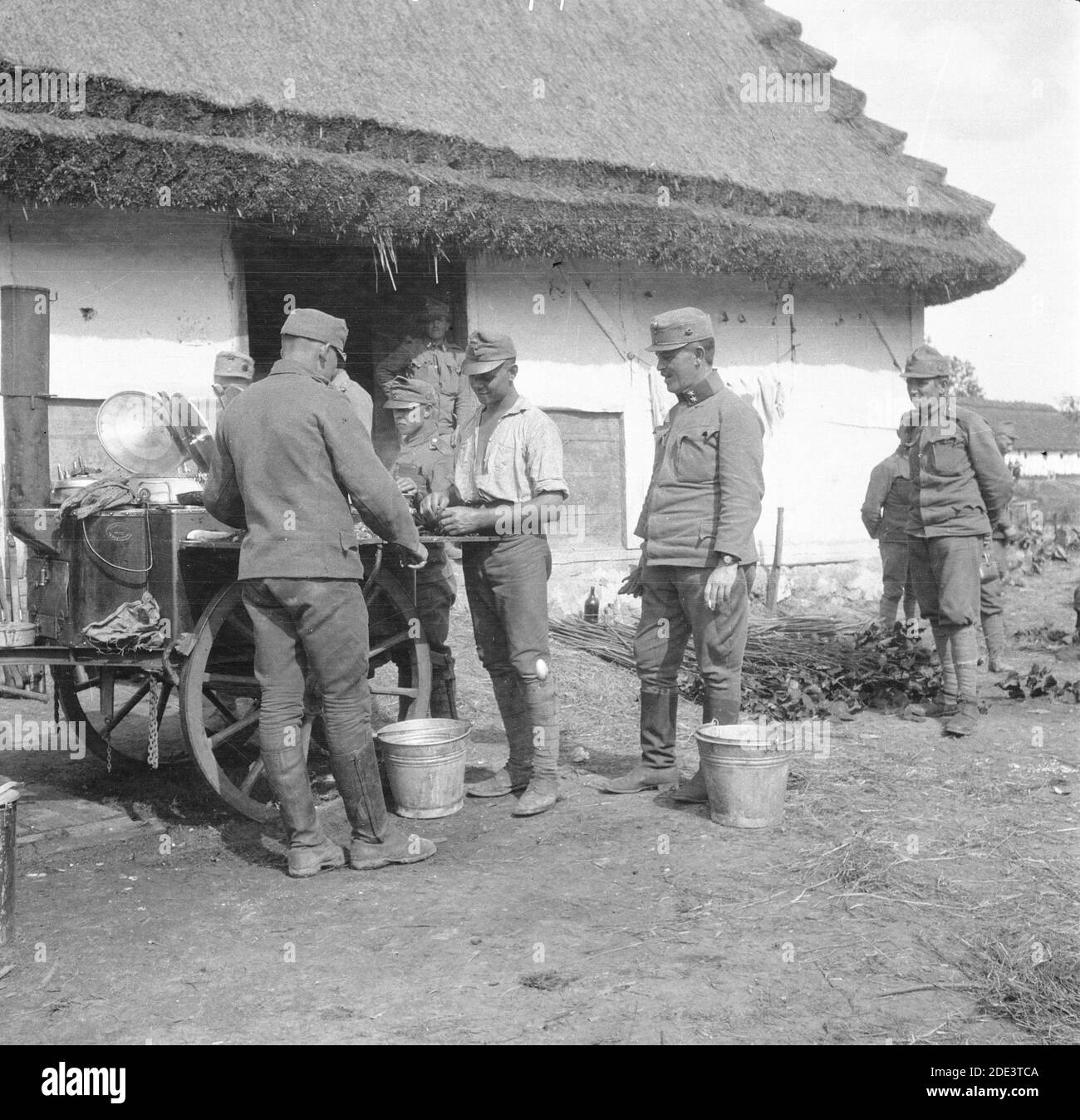 Armée austro-hongroise pendant la première Guerre mondiale. Des soldats se tenant autour d'une cuisine mobile en face d'une maison de campagne. Un soldat fumeur de cigarettes de rang 'korporal' se trouve au milieu. Date et lieu exacts incertains. Banque D'Images