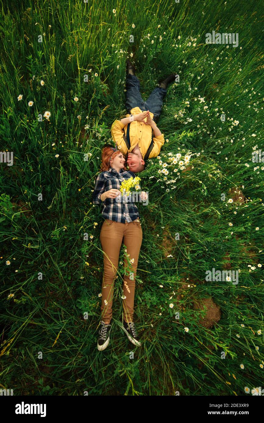 couple allongé dans un champ de fleurs. Un couple heureux se trouve dans une fleur. Scène romantique, émotionnelle et amoureuse Banque D'Images