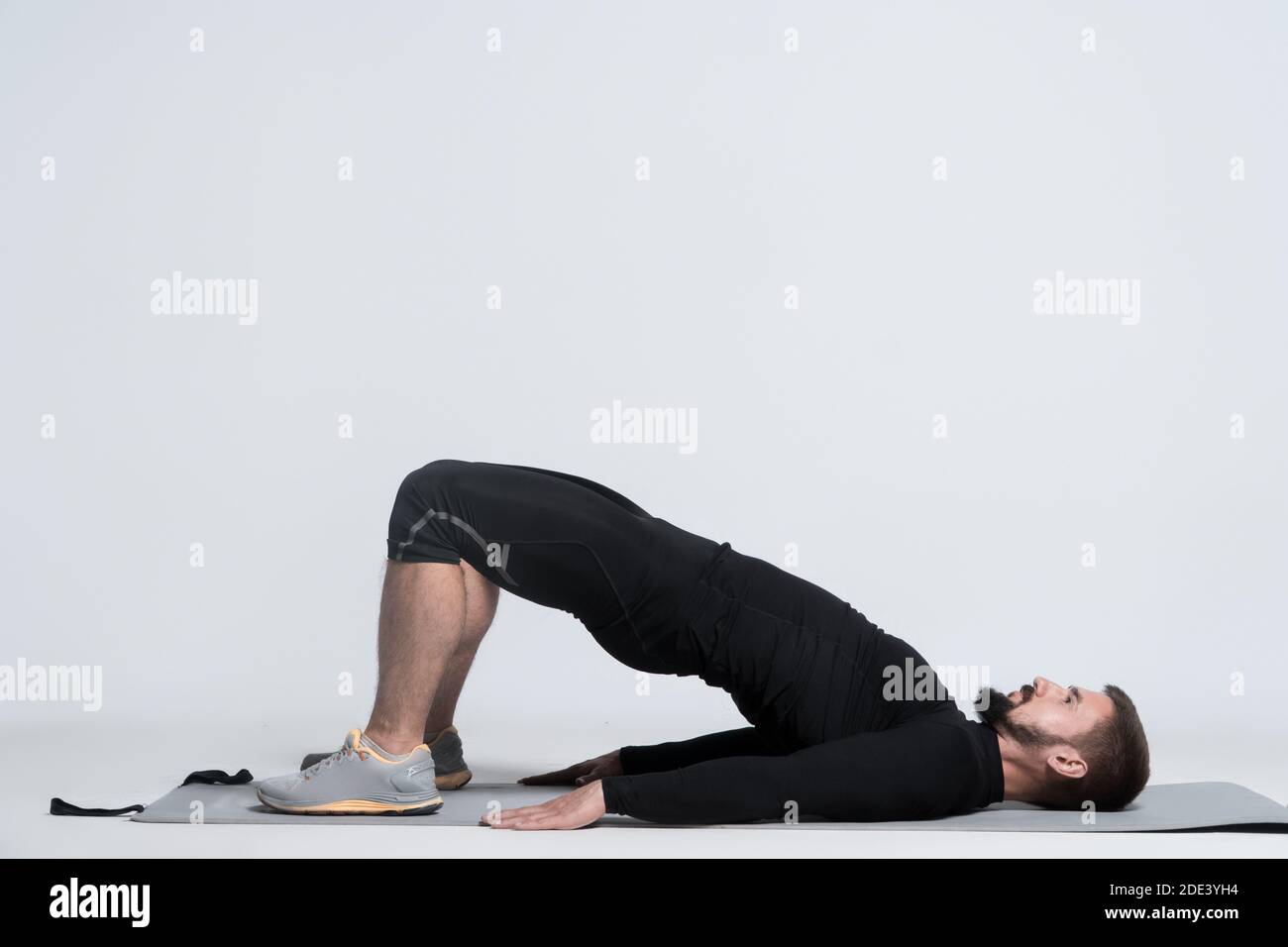 homme sportif faisant de l'exercice d'étirement et de l'entraînement sur tapis de yoga sur fond blanc Banque D'Images