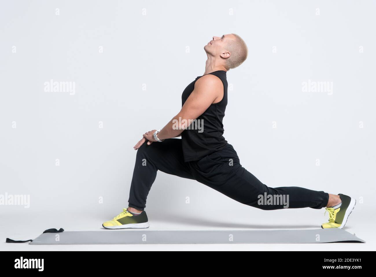 homme sportif faisant de l'exercice d'étirement et de l'entraînement sur tapis de yoga sur fond blanc Banque D'Images