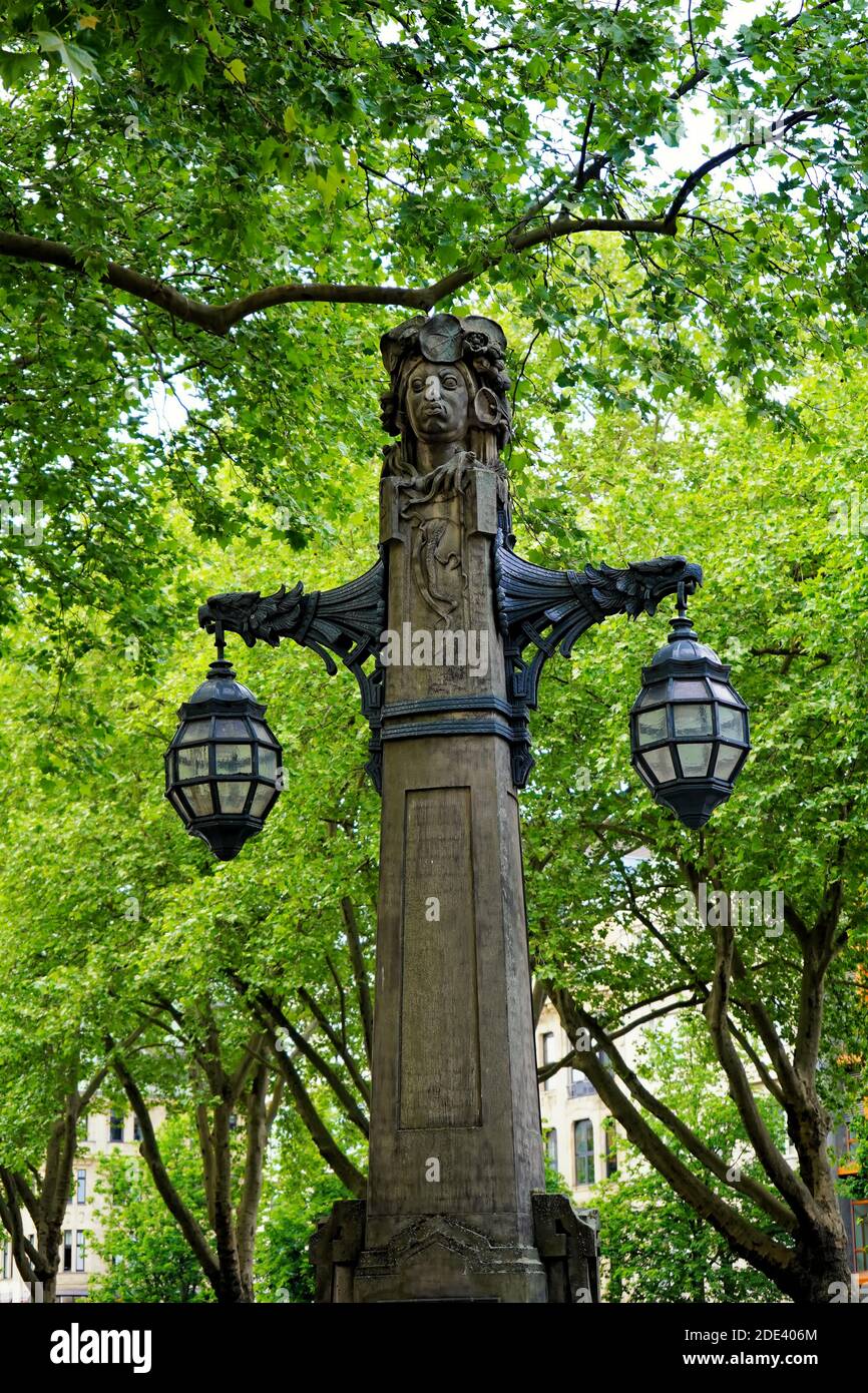 Ancienne lanterne de rue sur le boulevard commerçant Königsallee, dans le centre-ville de Düsseldorf, entourée de vieux arbres verts. Banque D'Images