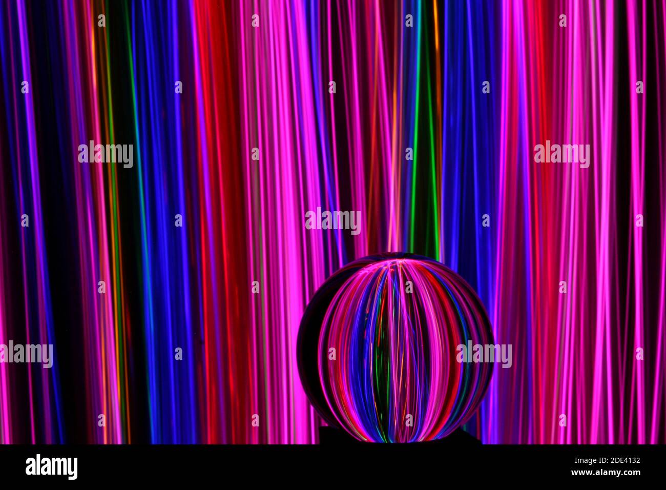 Photographie en exposition longue de néon multicolore dans un motif abstrait tourbillonnant avec boule de verre réfléchissante. Photographie de peinture légère. Banque D'Images