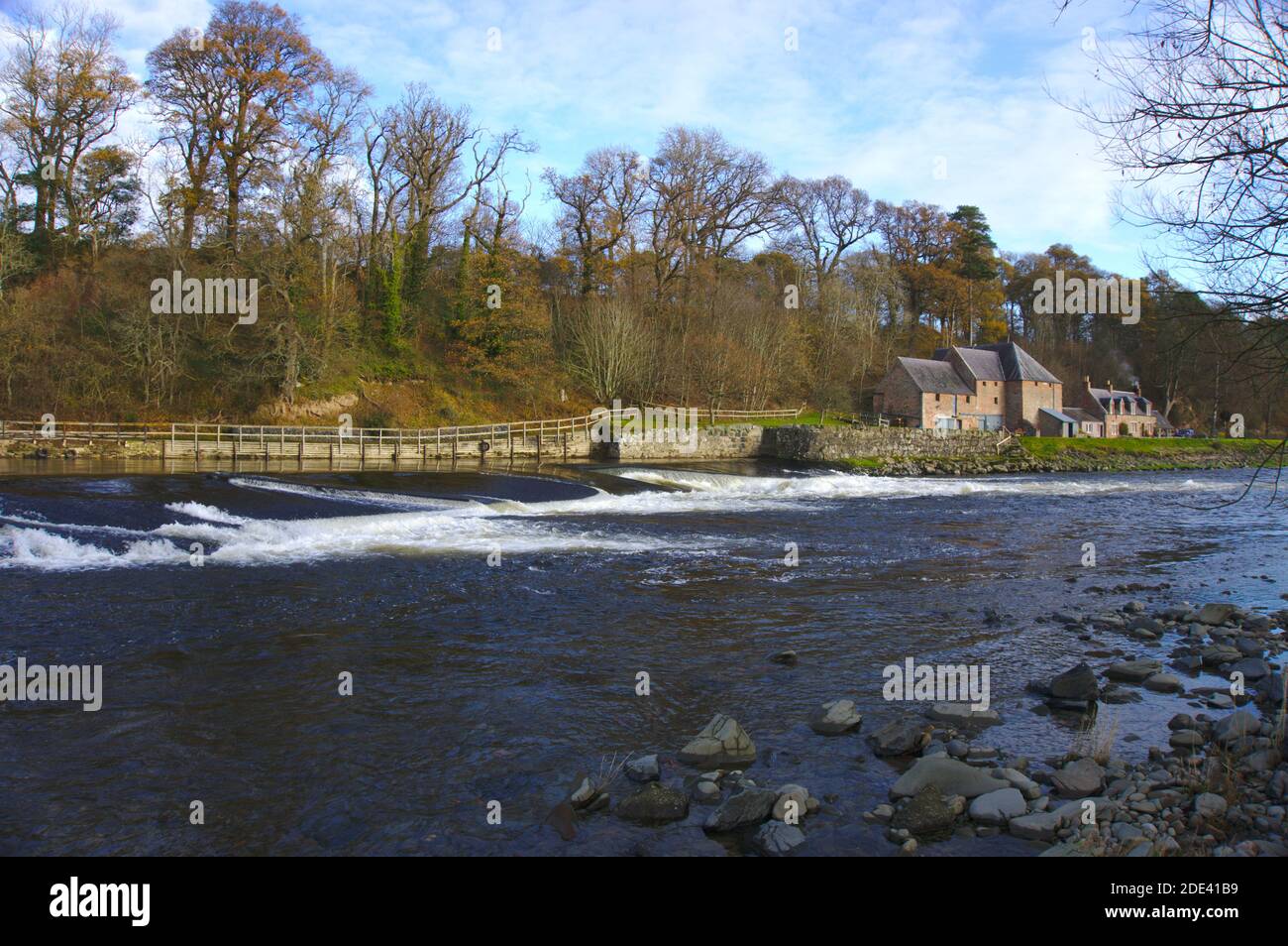 En regardant en aval sur la rivière Tweed vers Mertoun Weir avec Mertoun Mill en arrière-plan près de St Boswells, Roxburghshire, Scottish Borders, Royaume-Uni. Banque D'Images