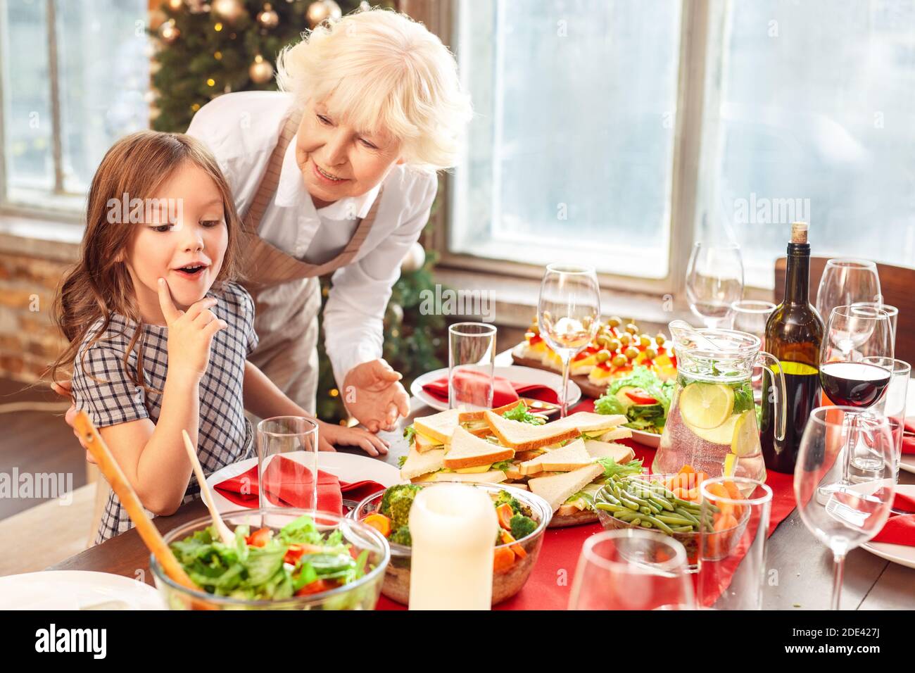 Petite fille affamée regardant la table de dîner servie Banque D'Images