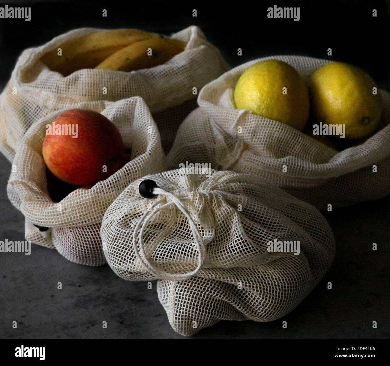 Quatre écobags en maille réutilisables avec différents fruits sur une table. Concept écologique. Orientation horizontale Banque D'Images