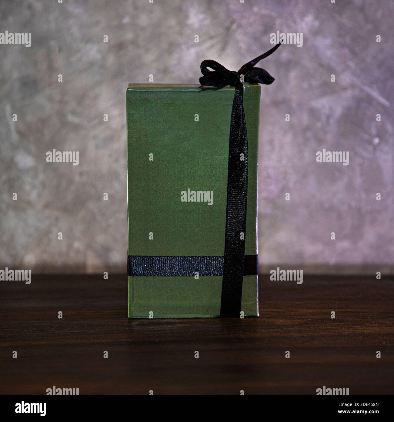 Boîte de parfum verte avec un ruban noir sur une obscurité table en bois Banque D'Images