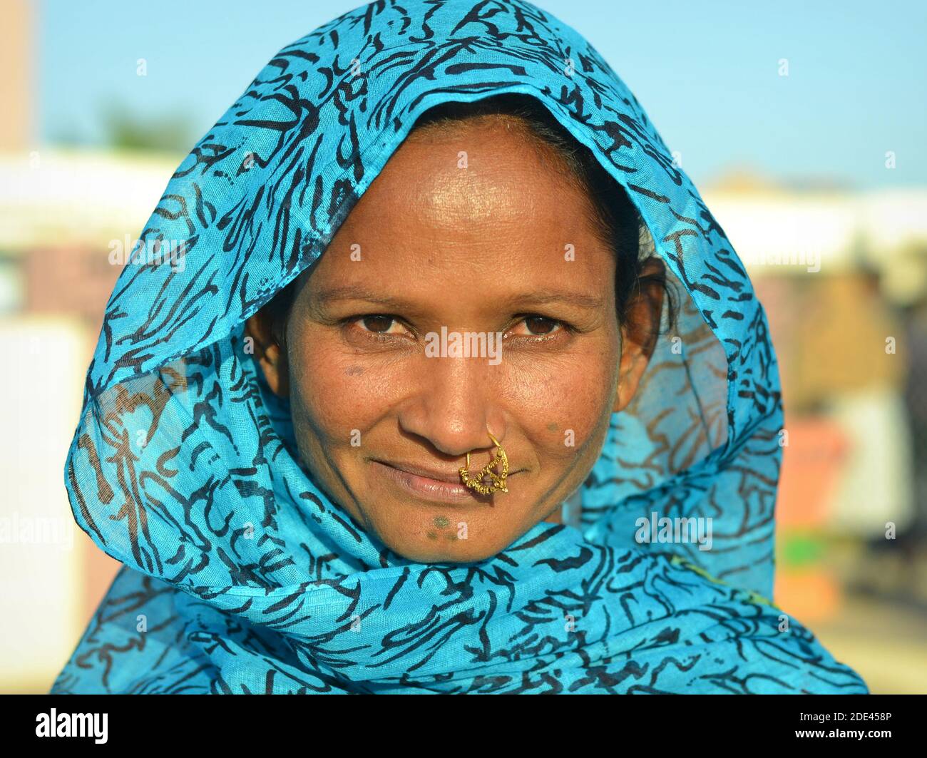 Jeune femme tribale indienne Rabari de Kutch avec bijoux précieux de nez et le tatouage traditionnel visage sur le menton pose dans la lumière du soleil pour l'appareil photo. Banque D'Images
