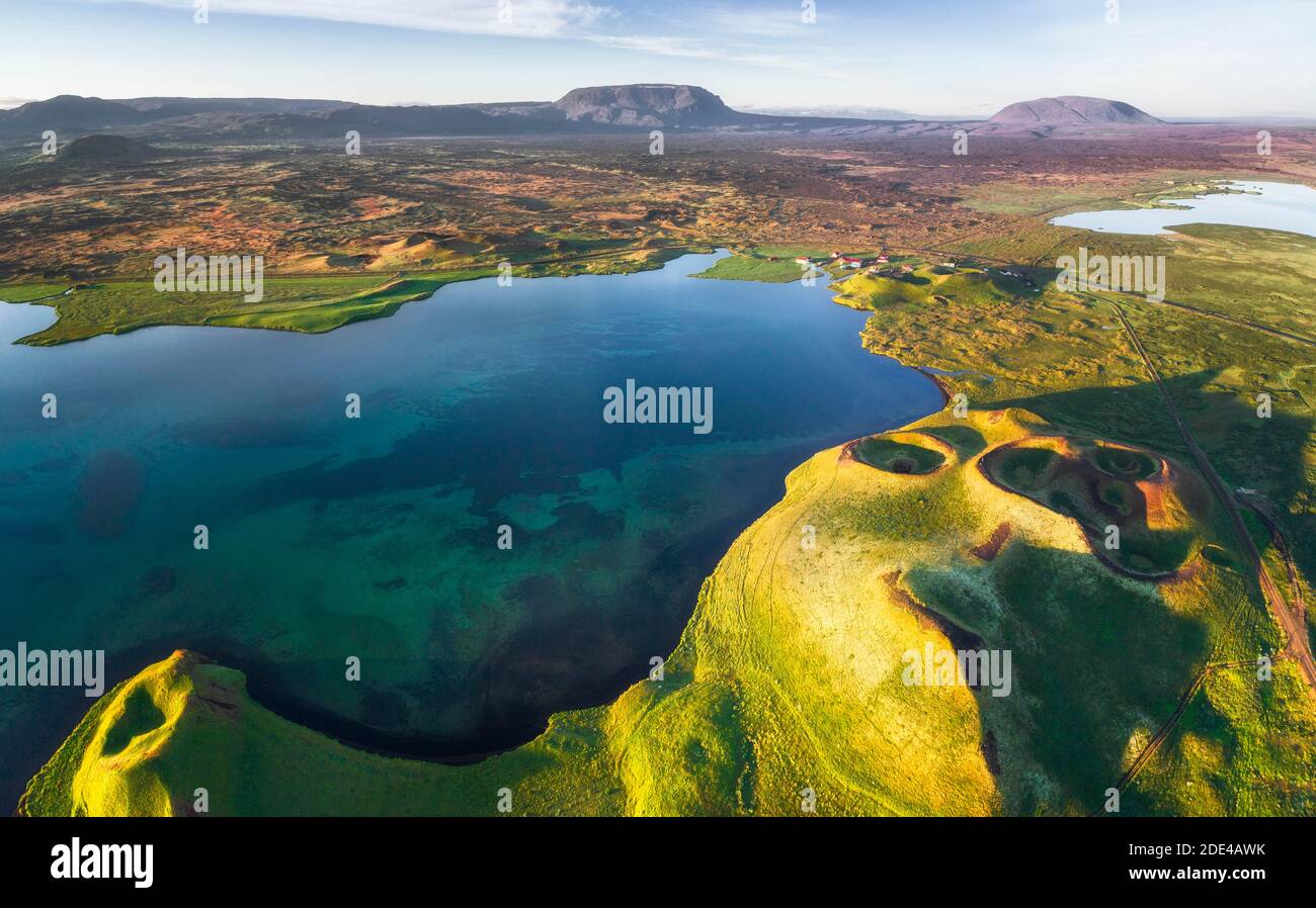 Vue aérienne de la côte avec des pseudo-cratères verts, cratères volcaniques, route et petites maisons avec des toits rouges dans le paysage volcanique derrière les montagnes au lac Banque D'Images