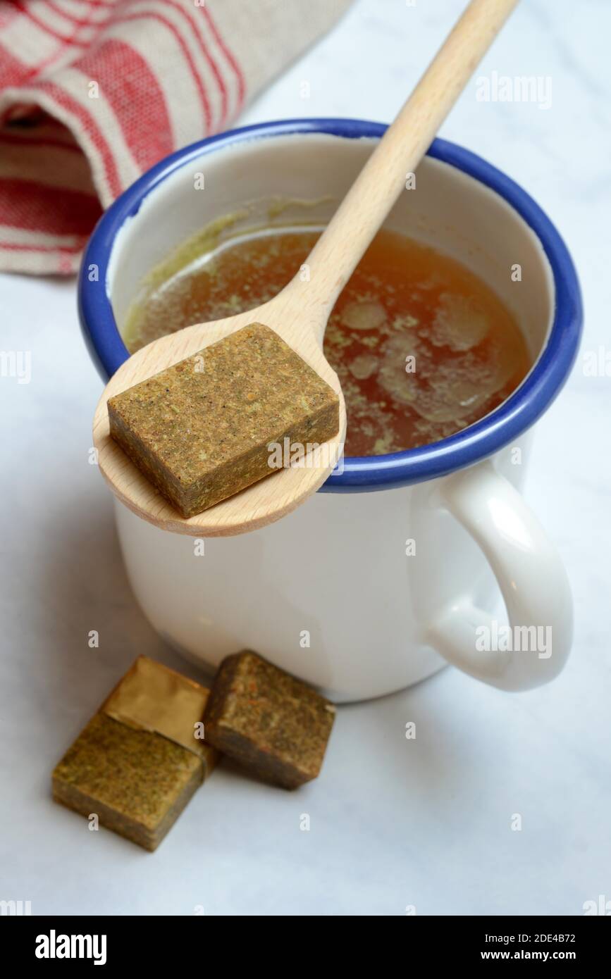 Tasse avec bouillon de bouillon et cubes de bouillon sur une cuillère en bois, Allemagne Banque D'Images