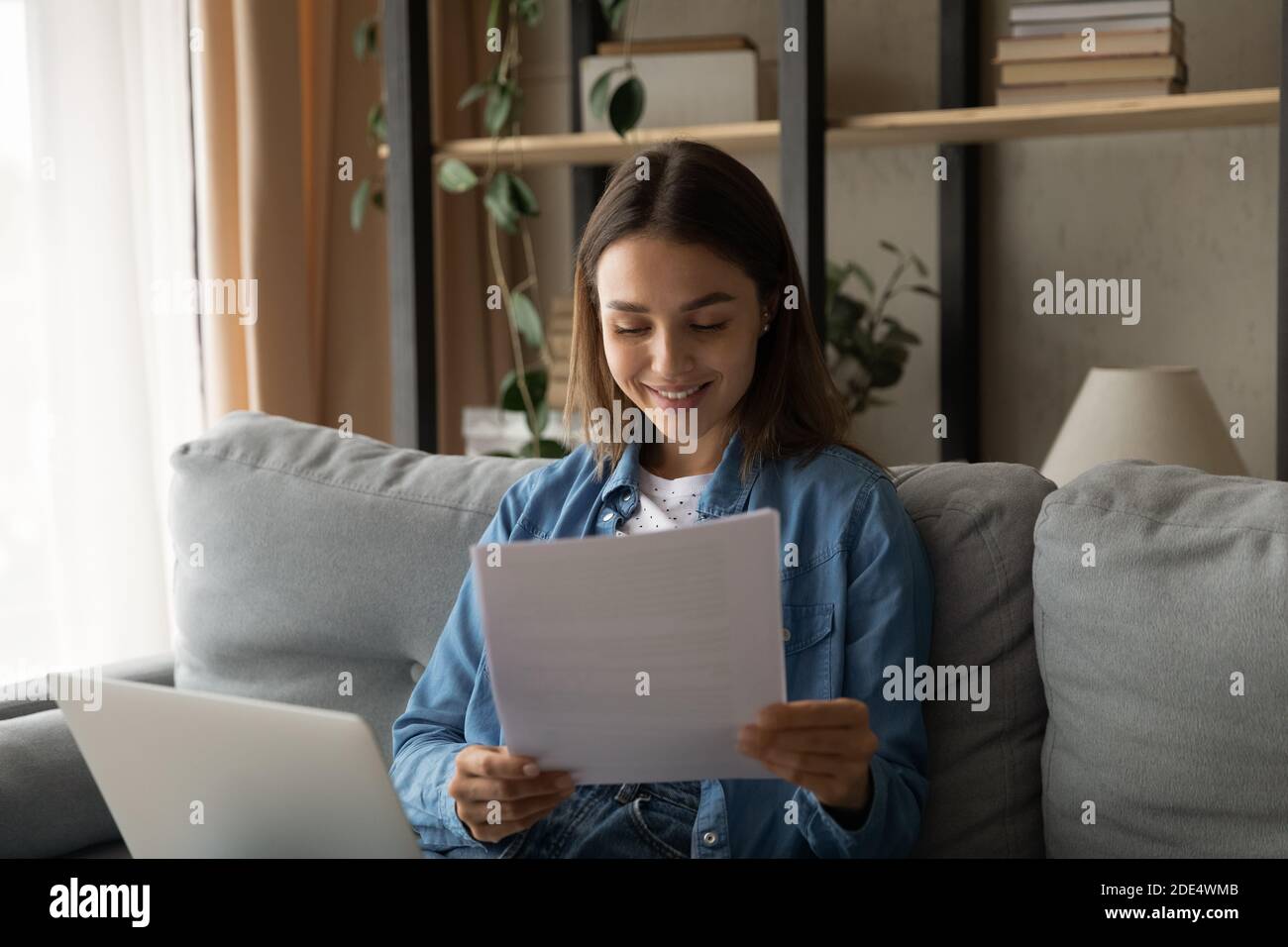 Une femme heureuse travaille sur des documents de lecture d'ordinateur portable Banque D'Images