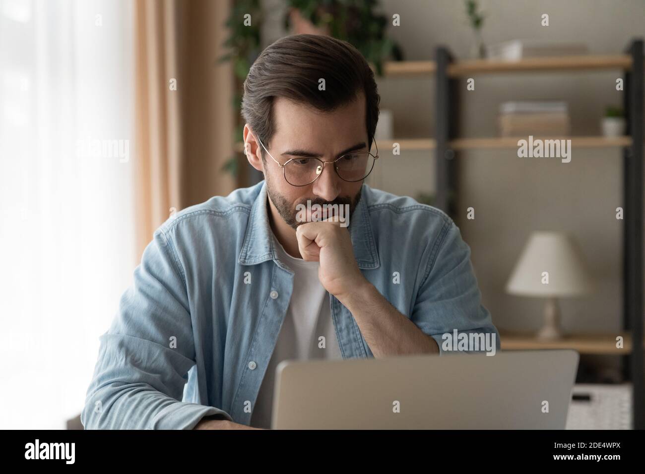 Un homme caucasien pensif regarde l'écran d'ordinateur portable de réflexion Banque D'Images