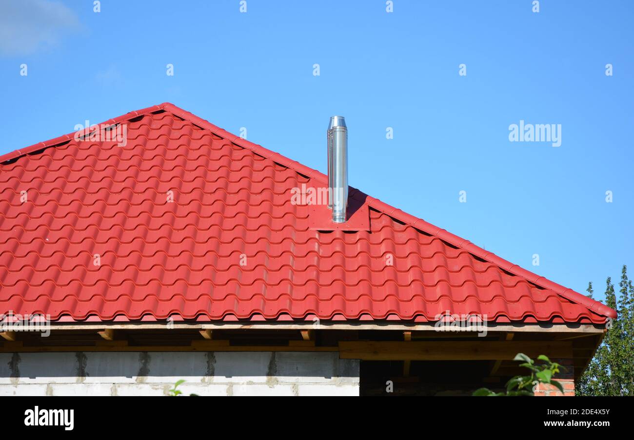 Tuiles de toit en métal rouge léger Construction de toiture avec cheminée en acier. Banque D'Images