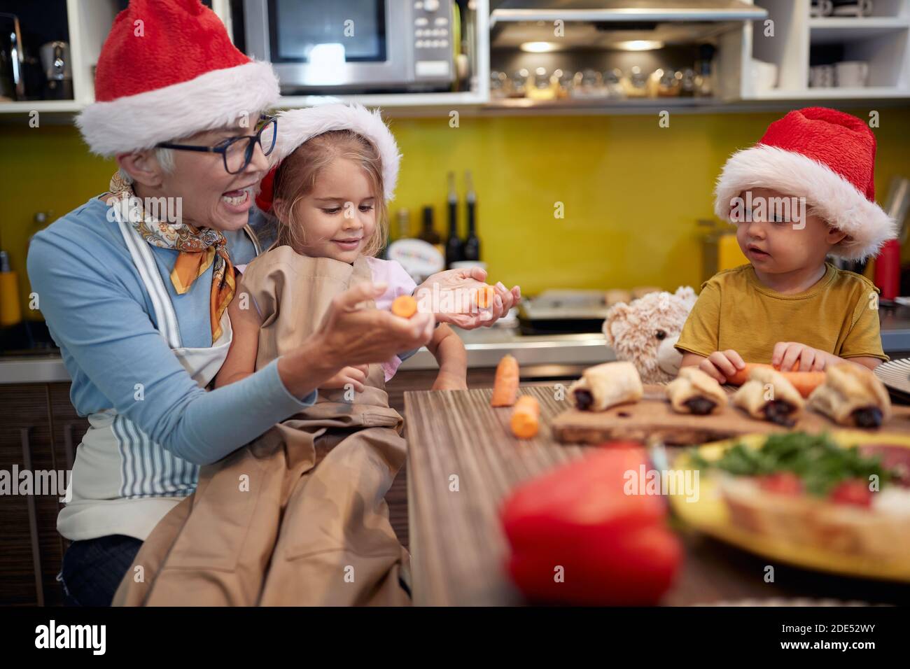 Grand-mère et petits-enfants préparant des repas de Noël dans la cuisine dans une atmosphère gaie ensemble. Noël, famille, ensemble Banque D'Images