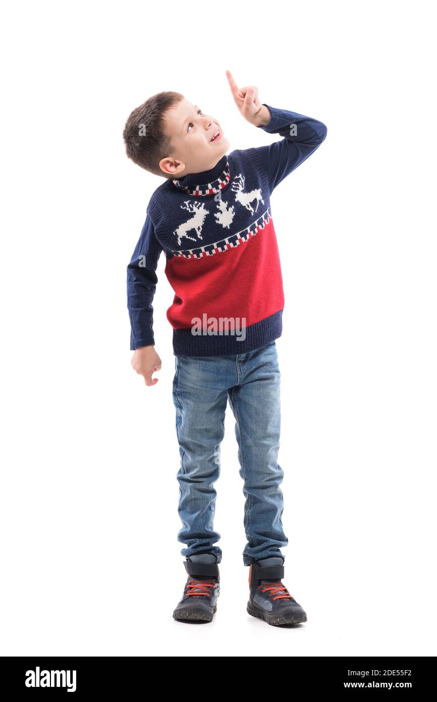 Joyeux jeune enfant dans le chandail de Noël en utilisant l'écran tactile de réalité virtuelle pointant le doigt vers le haut. Portrait du corps entier isolé sur fond blanc. Banque D'Images