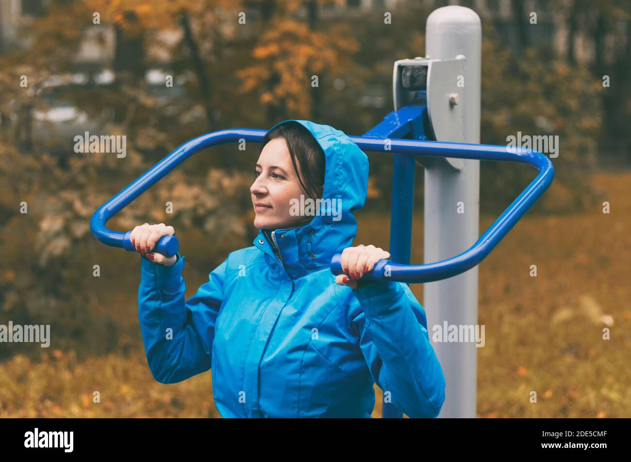 En automne, une jeune femme va pour les sports de plein air se tenir sur les mains courantes d'un simulateur sportif Banque D'Images