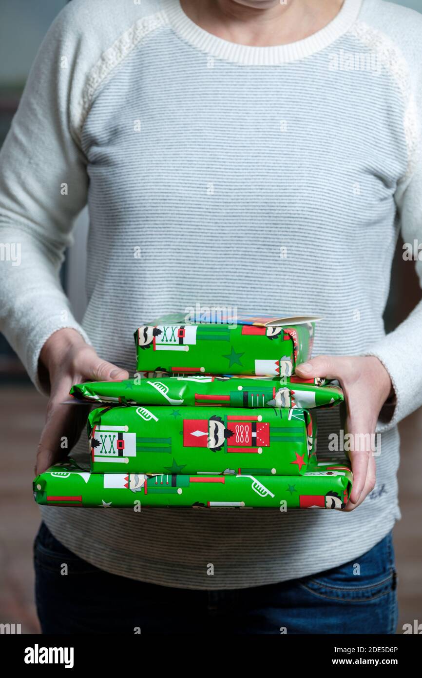 Une femme tenant une petite pile de cadeaux de Noël enveloppée Papier cadeau de Noël aux couleurs vives Banque D'Images