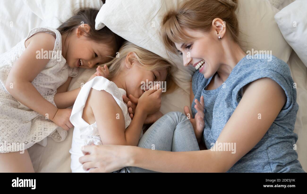 Vue de dessus une mère pleine de joie et deux petites filles allongées ensemble Banque D'Images