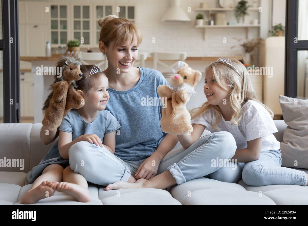 Jeune mère souriante avec deux petites filles jouant au théâtre de poupée Banque D'Images