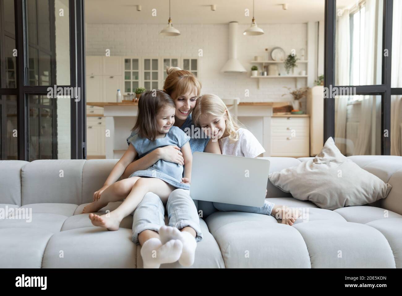Bonne jeune mère avec deux petites filles utilisant un ordinateur portable ensemble Banque D'Images